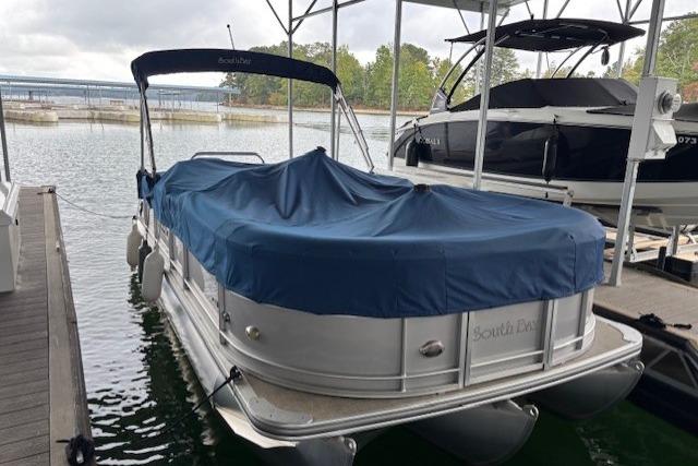 2017 South Bay 222 RS pontoon boat docked with blue cover on a lake.