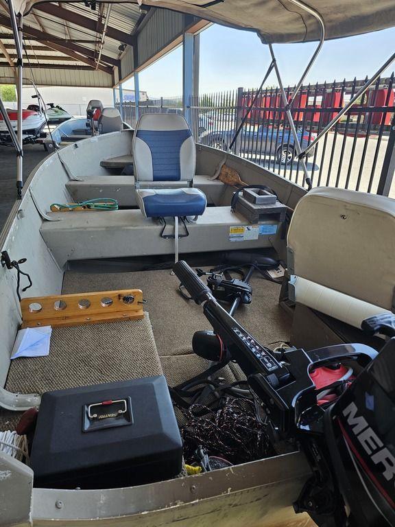 2003 Alumacraft V14 boat interior with seating, motor, and equipment under a canopy.