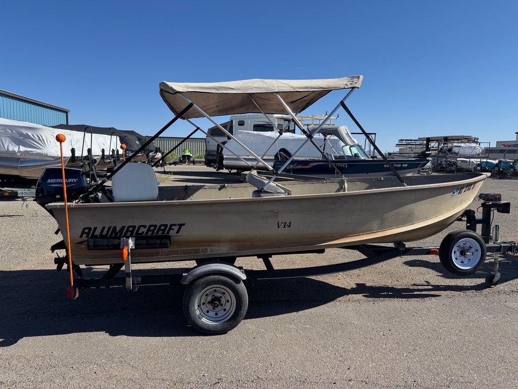 2003 Alumacraft V14 boat on trailer with canopy, parked outdoors.