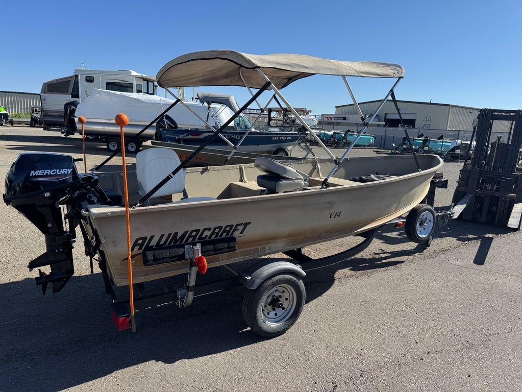 2003 Alumacraft V14 boat with Mercury motor on trailer, parked outdoors.