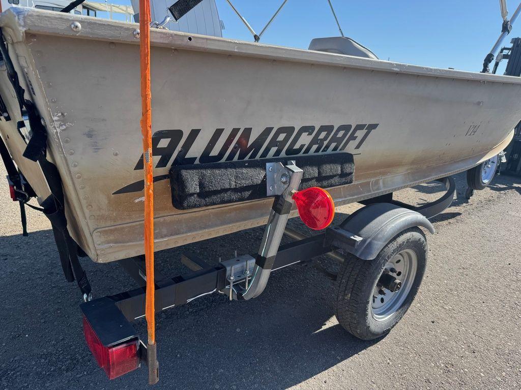 2003 Alumacraft V14 boat on trailer, side view with visible logo and wheel.