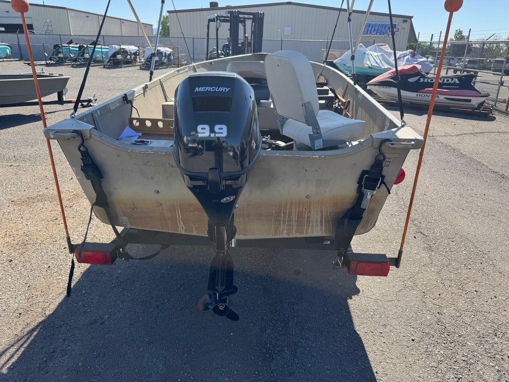 2003 Alumacraft V14 boat with Mercury 9.9 motor in a storage yard.