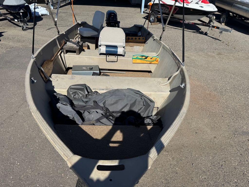 2003 Alumacraft V14 boat with seating and equipment, parked on pavement.