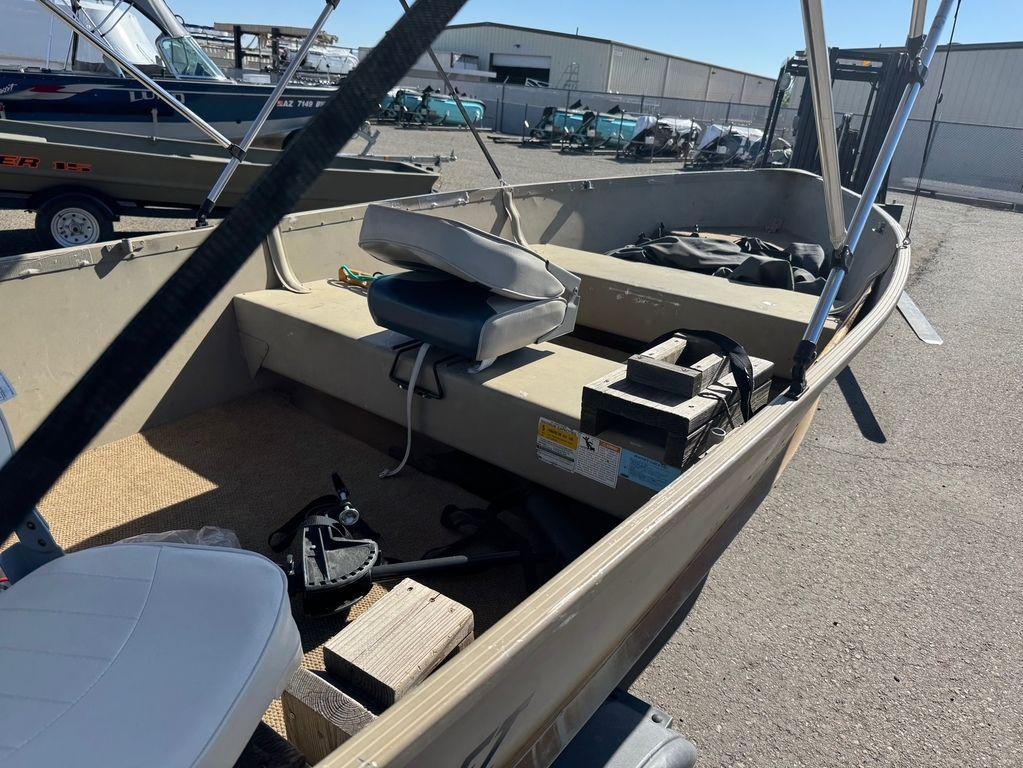 2003 Alumacraft V14 boat interior with seats and equipment, parked outdoors.