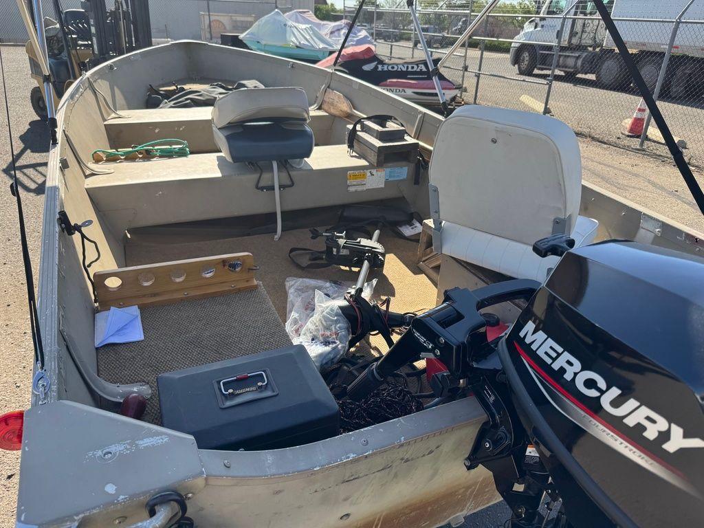 2003 Alumacraft V14 boat with Mercury outboard motor, parked in a lot.