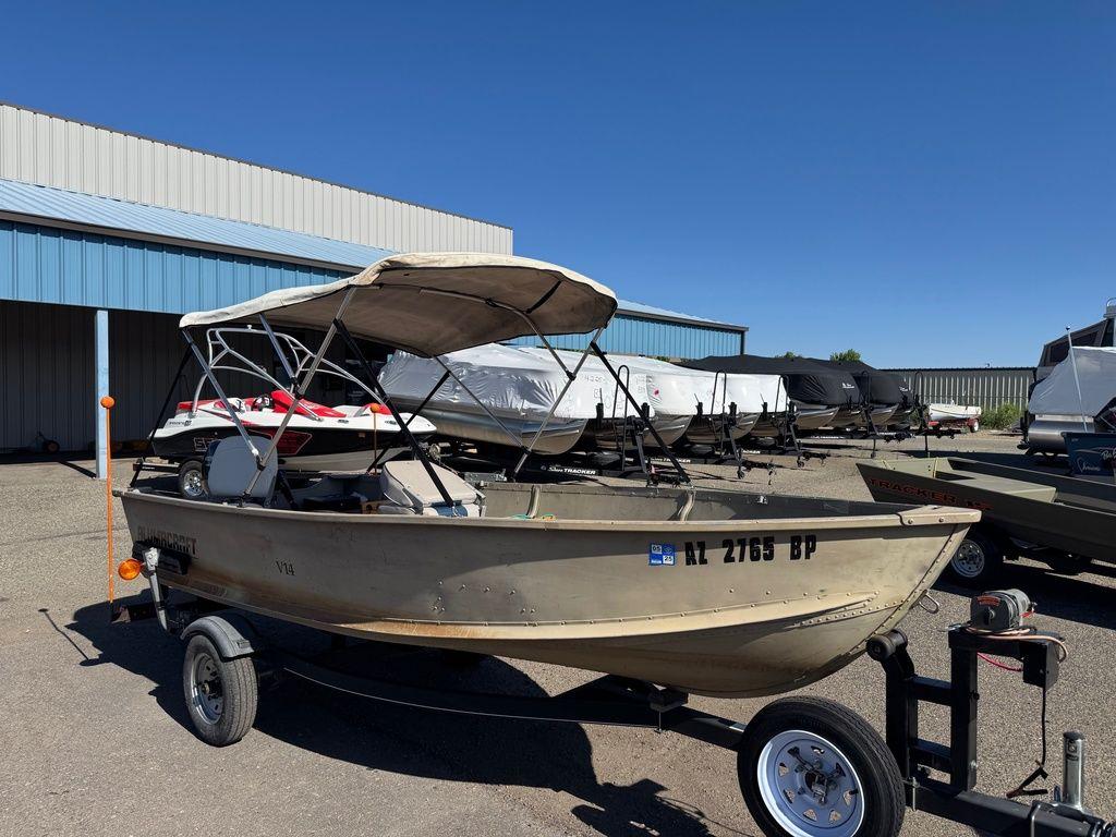 2003 Alumacraft V14 boat with canopy on trailer, parked outdoors.