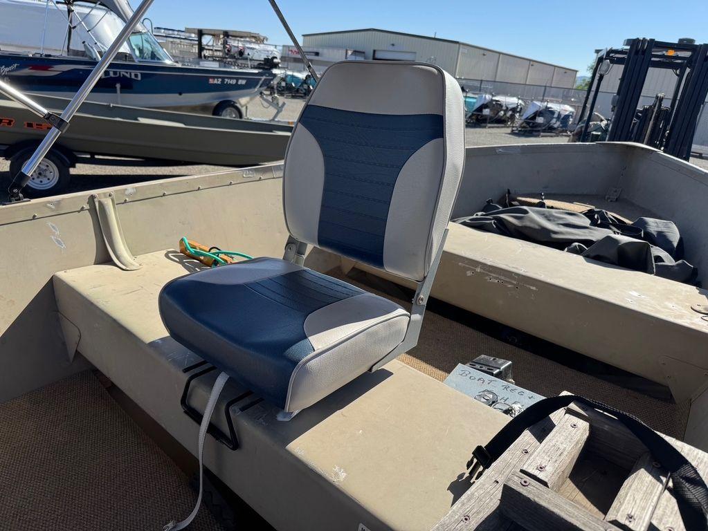 2003 Alumacraft V14 boat interior with blue and white seat, docked in a marina.