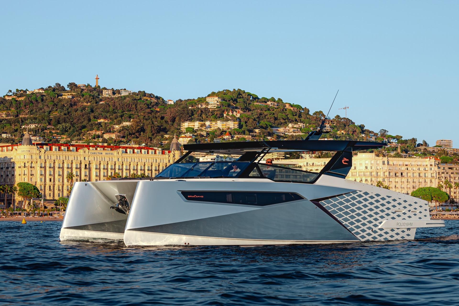 2026 Dracan 42 Catamaran cruising near scenic coastal city backdrop.