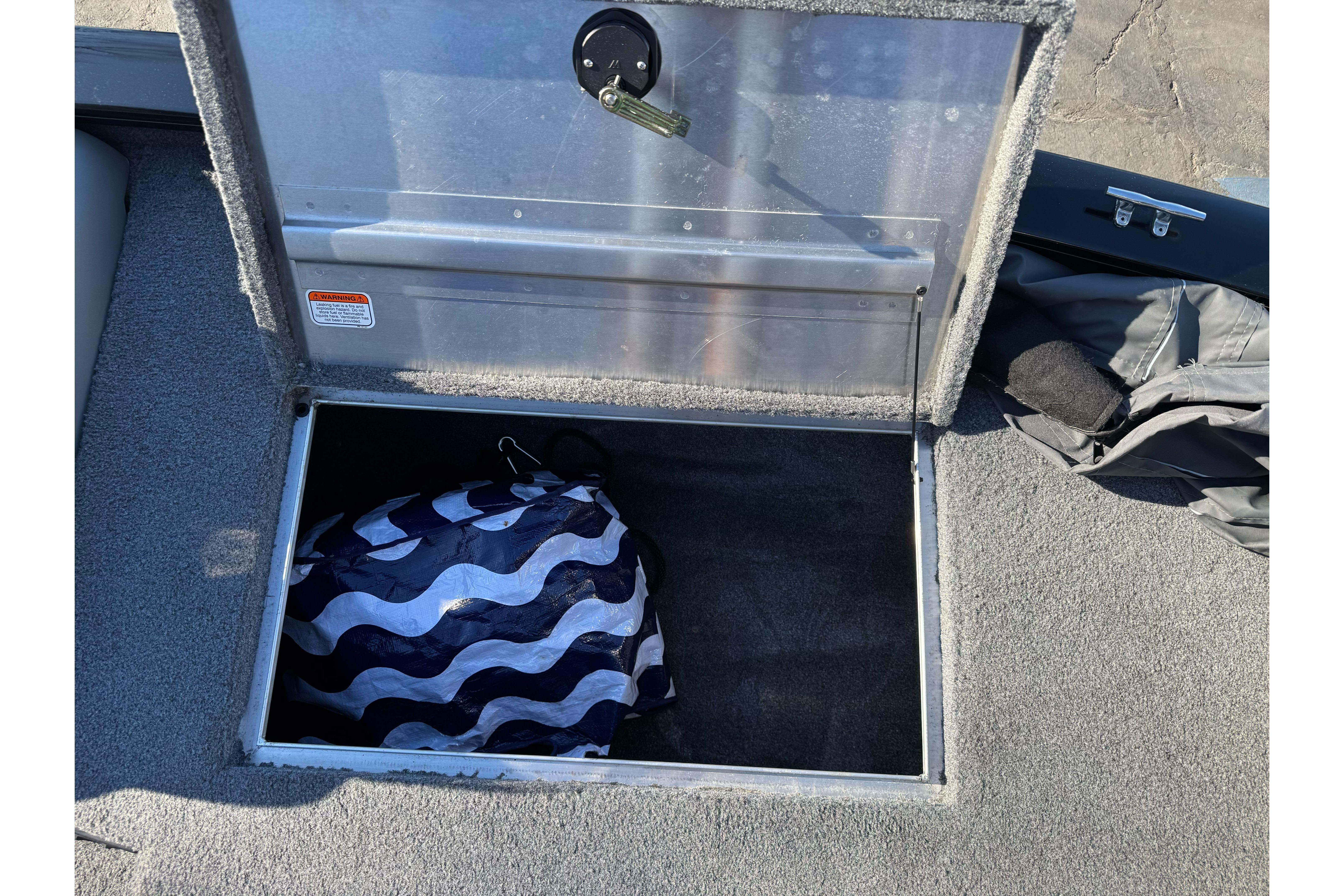 Open storage compartment on 2017 Tracker Pro Team 195 TXW boat with wavy-patterned bag inside.