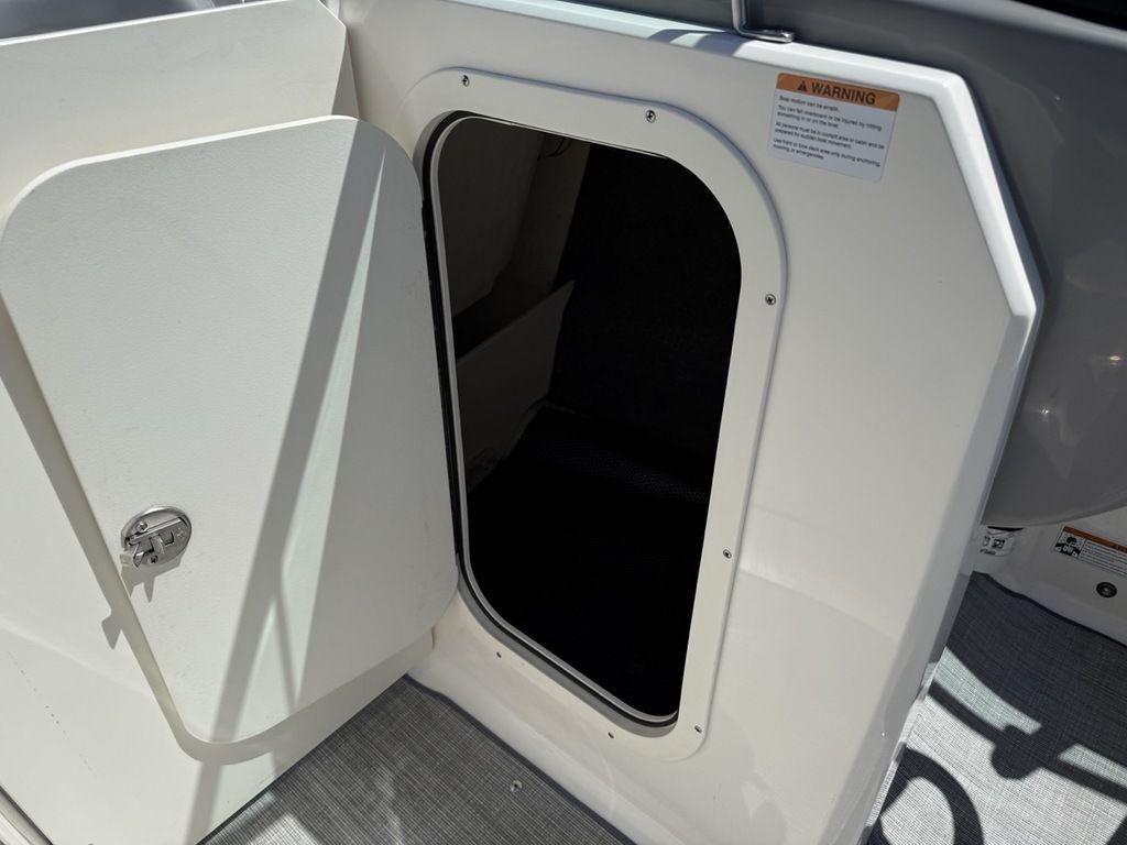 2022 Chaparral 23 SSi boat storage compartment with open door and warning label.