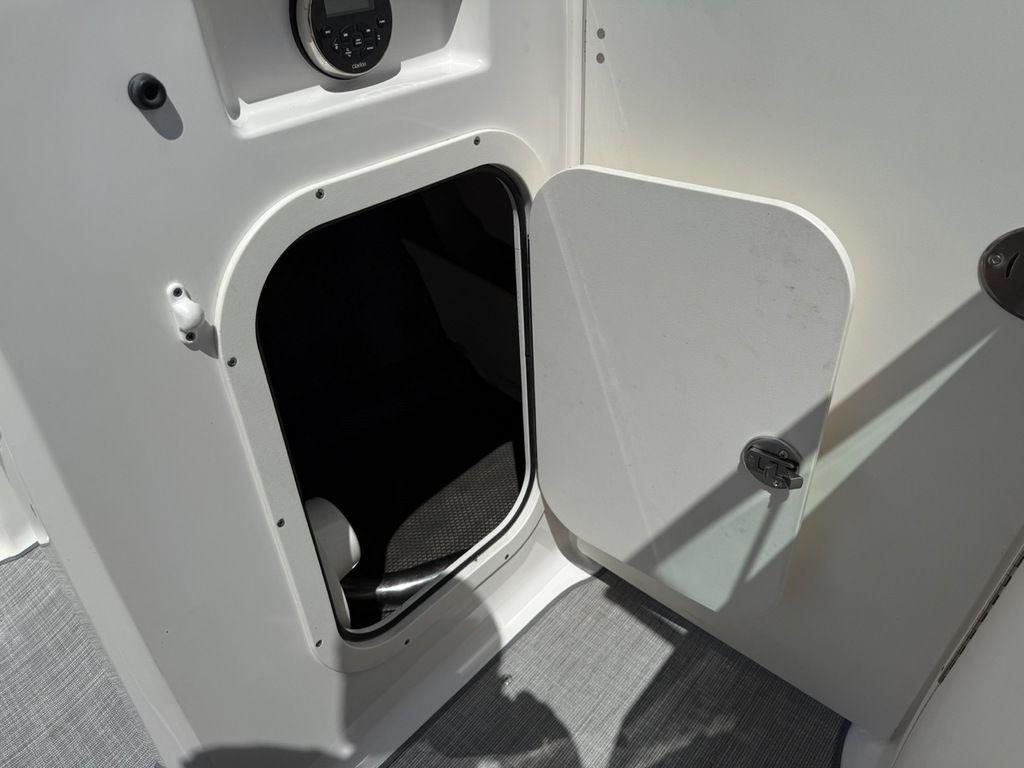 Open storage compartment on 2022 Chaparral 23 SSi boat, featuring a white interior.