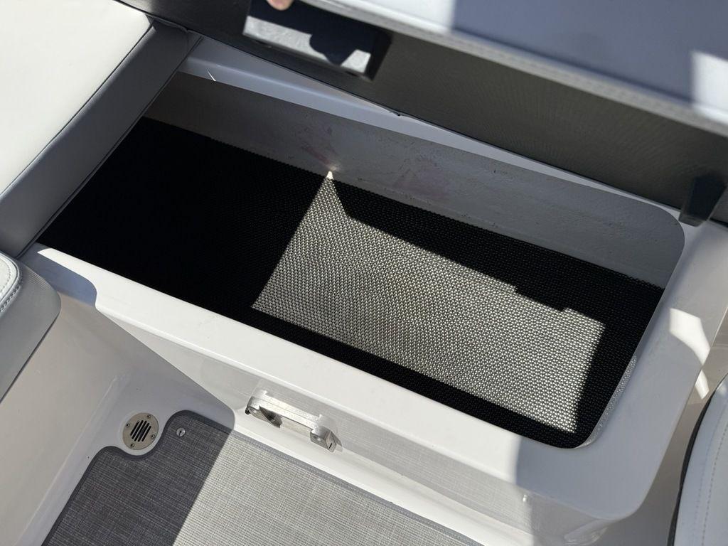 2022 Chaparral 23 SSi boat storage compartment with open lid, showcasing interior space.