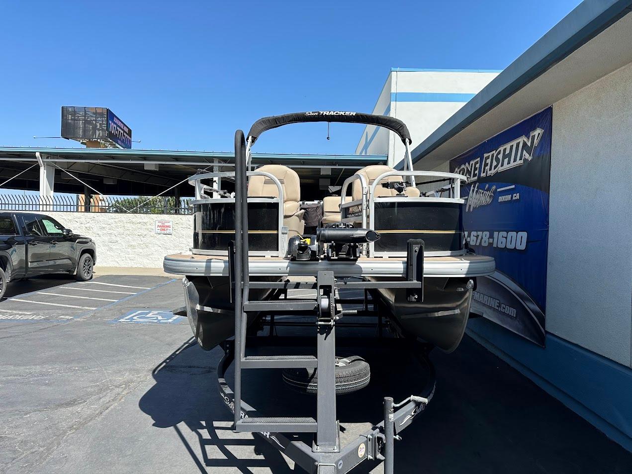 2022 Sun Tracker Bass Buggy 16 XL Select pontoon boat on trailer, parked outdoors.