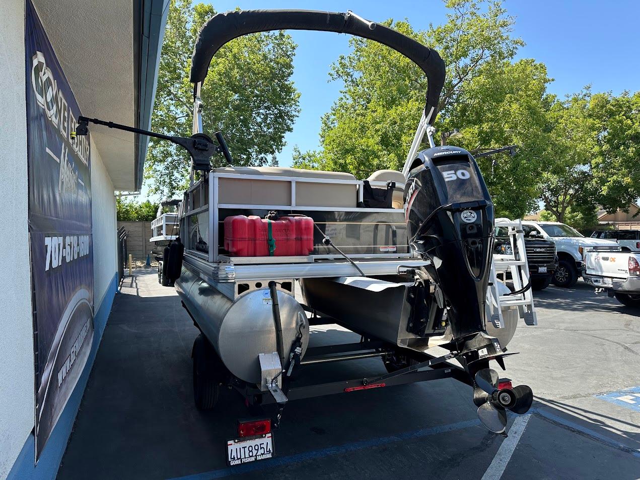 2022 Sun Tracker Bass Buggy 16 XL Select pontoon boat with outboard motor, parked outdoors.