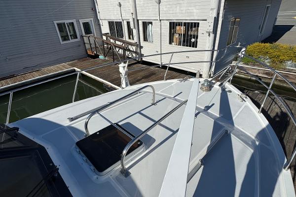 1991 Ocean Alexander 46 yacht bow with railing, docked near wooden buildings.