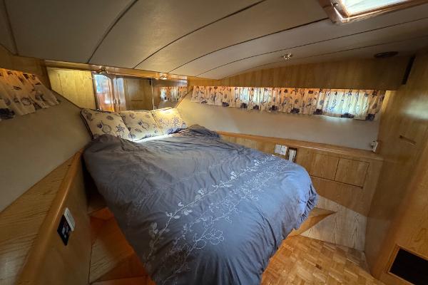 Cozy bedroom in 1991 Ocean Alexander 46 yacht with floral curtains and wooden cabinetry.