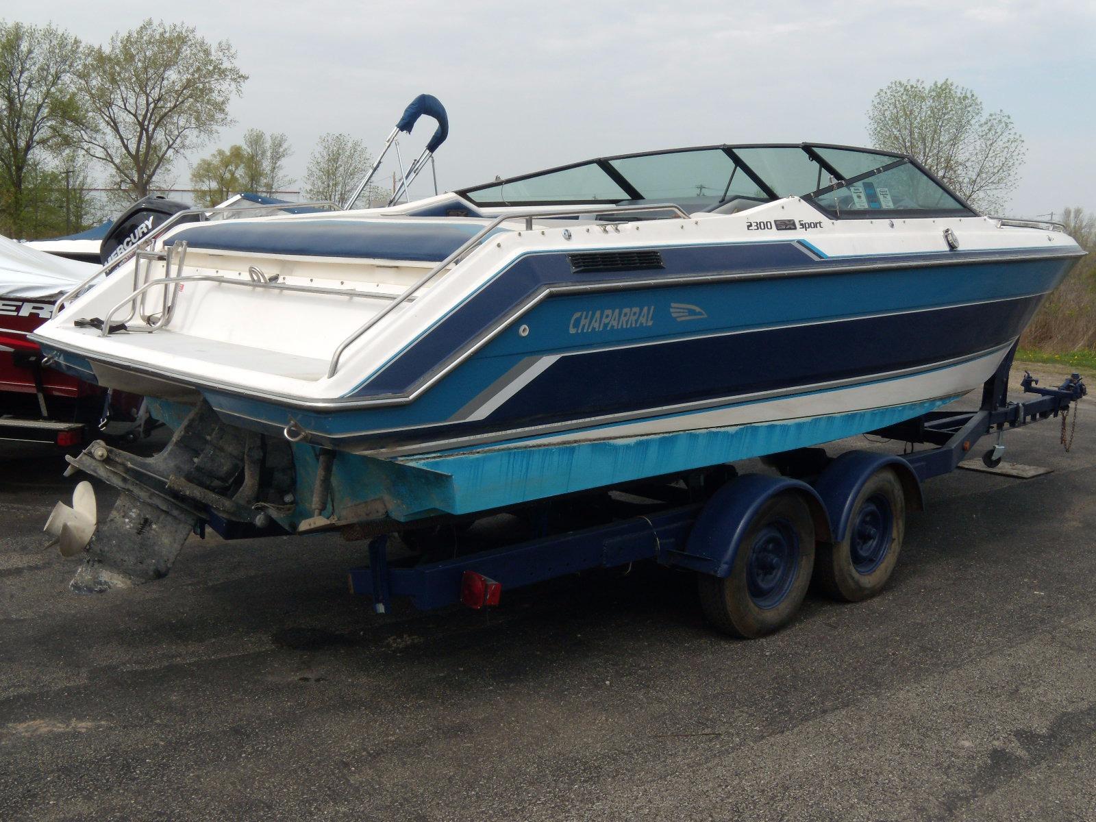 1989 Chaparral 2300 SX Sport boat on trailer, blue and white design, parked outdoors.