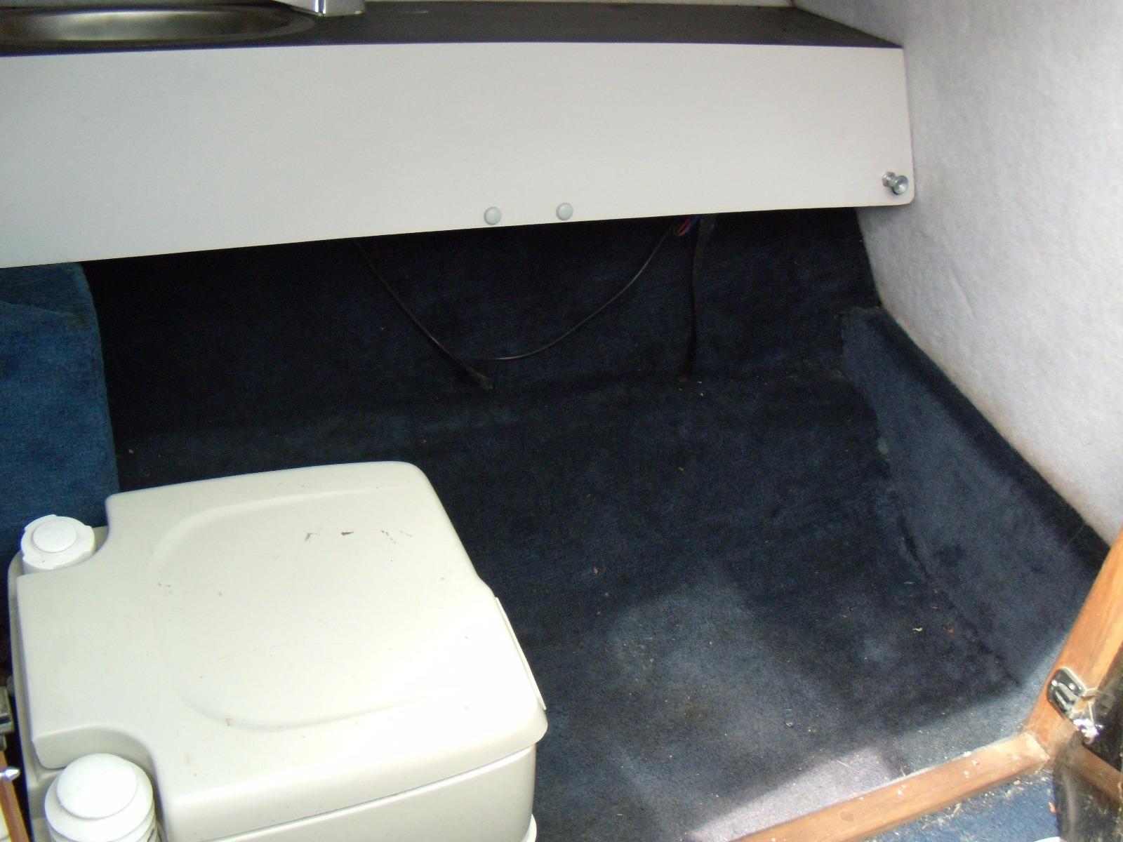 Interior cabin of 1989 Chaparral 2300 SX Sport boat with storage and portable toilet.