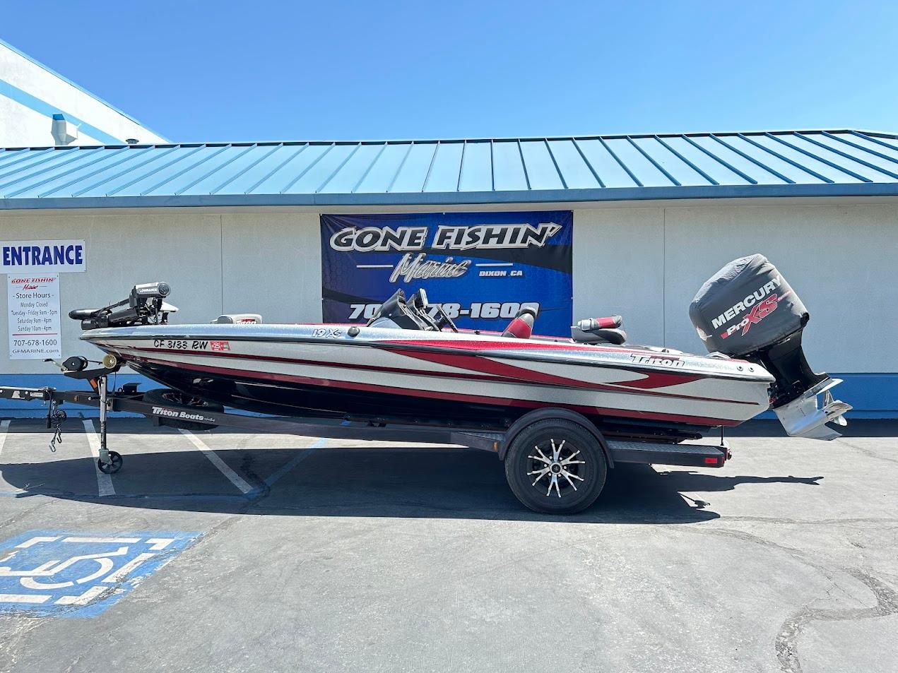 2013 Triton 19XS boat with Mercury engine parked outside a fishing store.