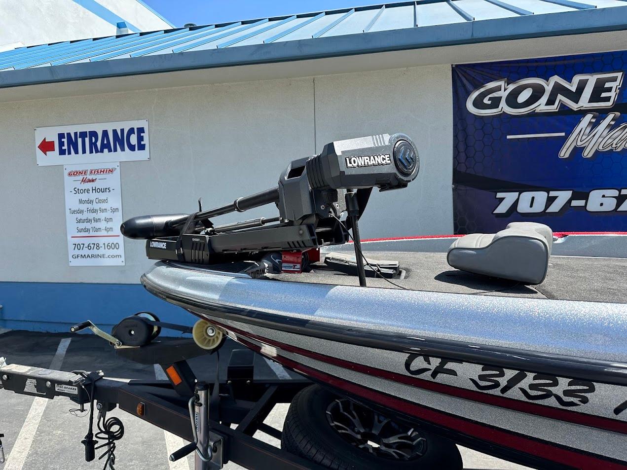2013 Triton 19XS boat with Lowrance equipment on trailer, parked outside a store.