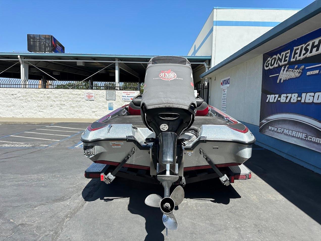 2013 Triton 19XS boat with motor cover, parked outside a marine shop.