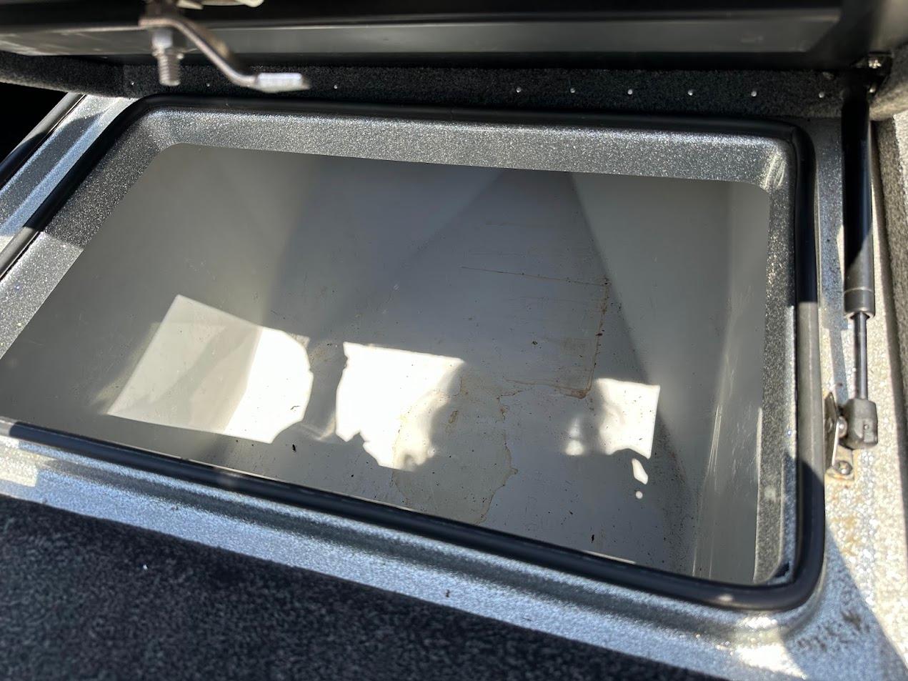 Open storage compartment in a 2013 Triton 19XS boat, showing interior space.