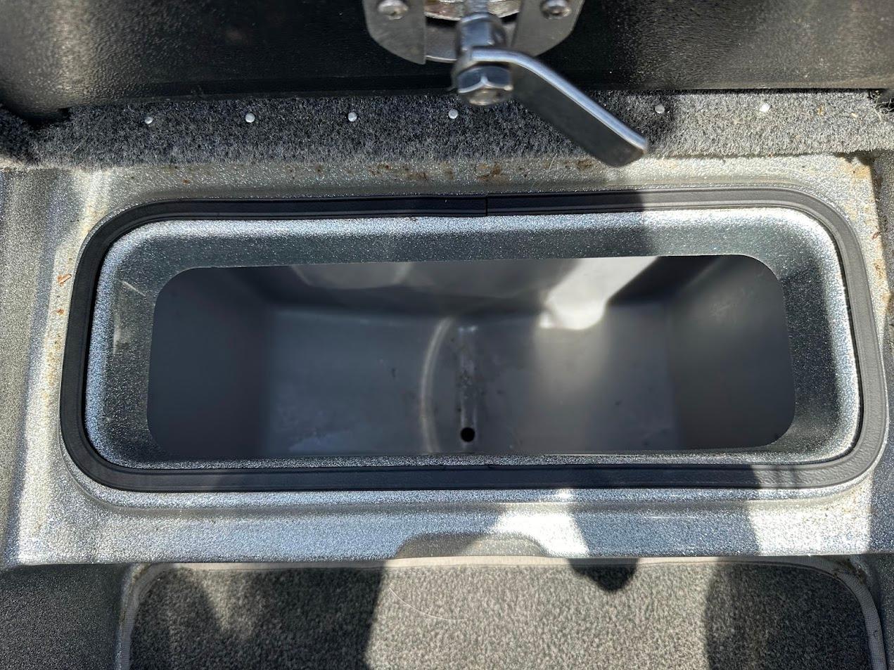Open storage compartment in a 2013 Triton 19XS boat, featuring a latch handle.