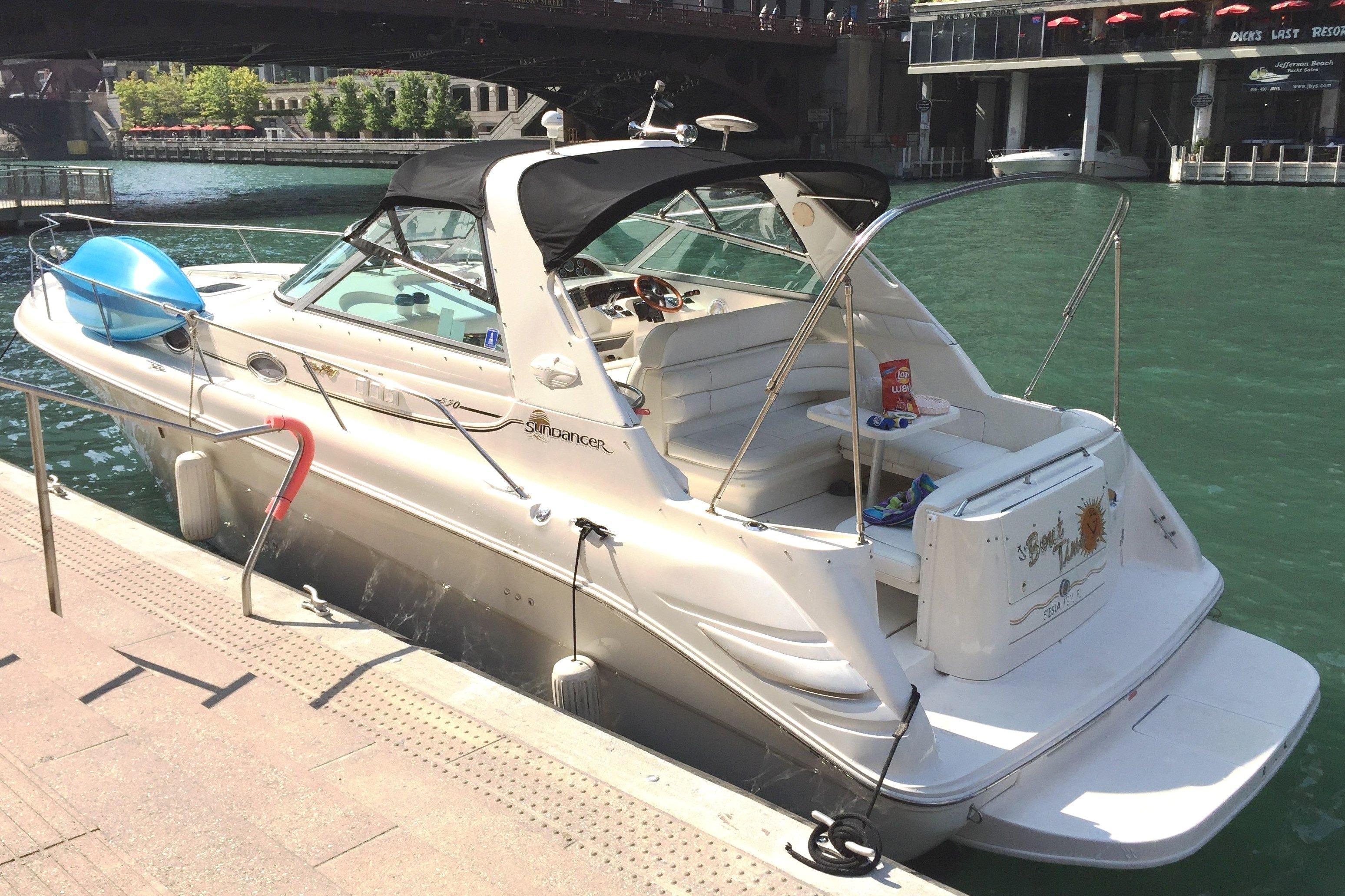 1997 Sea Ray Sundancer 330 docked by a riverside, featuring sleek design and spacious seating.