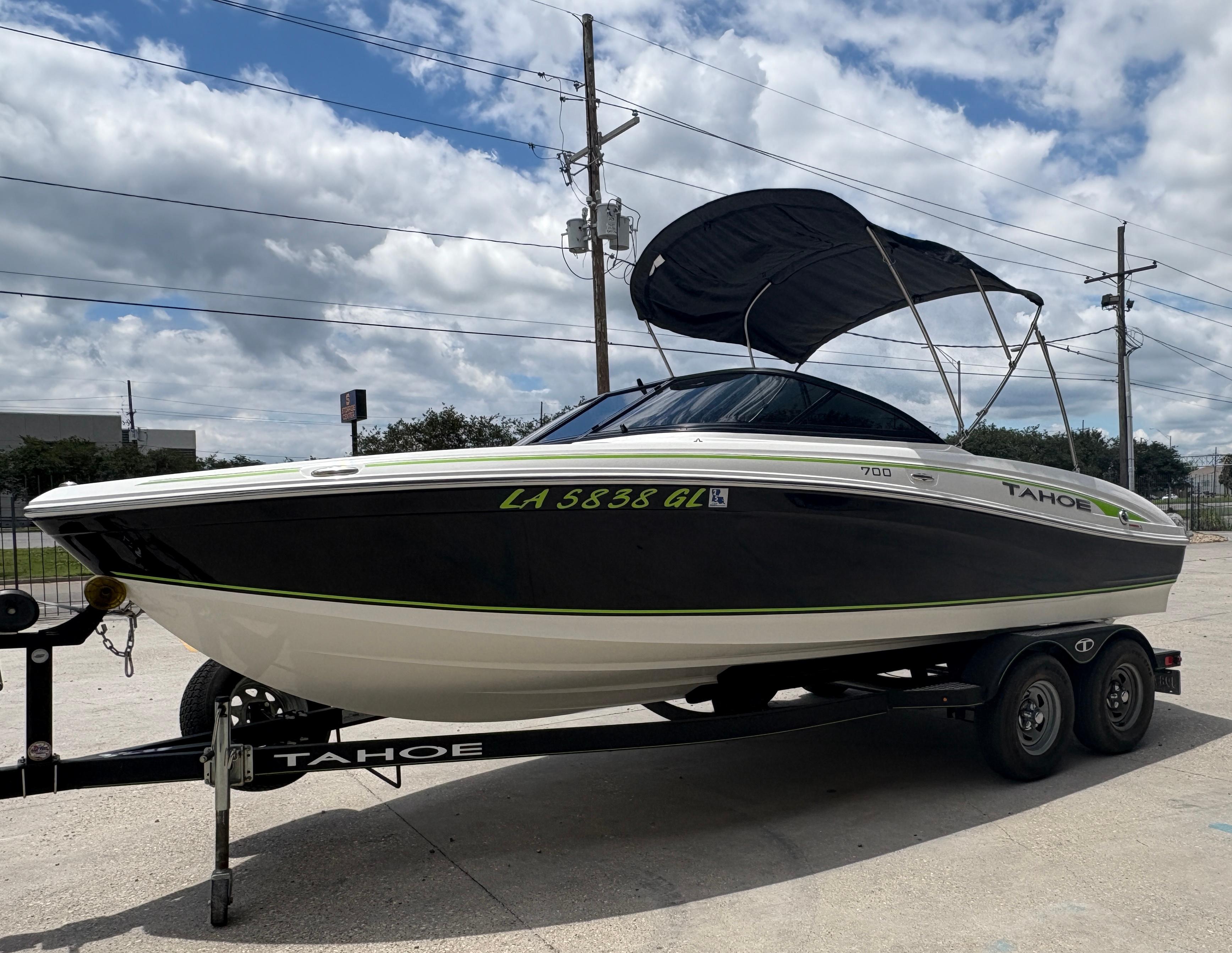 2019 Tahoe 700 boat on trailer with canopy, parked outdoors under cloudy sky.