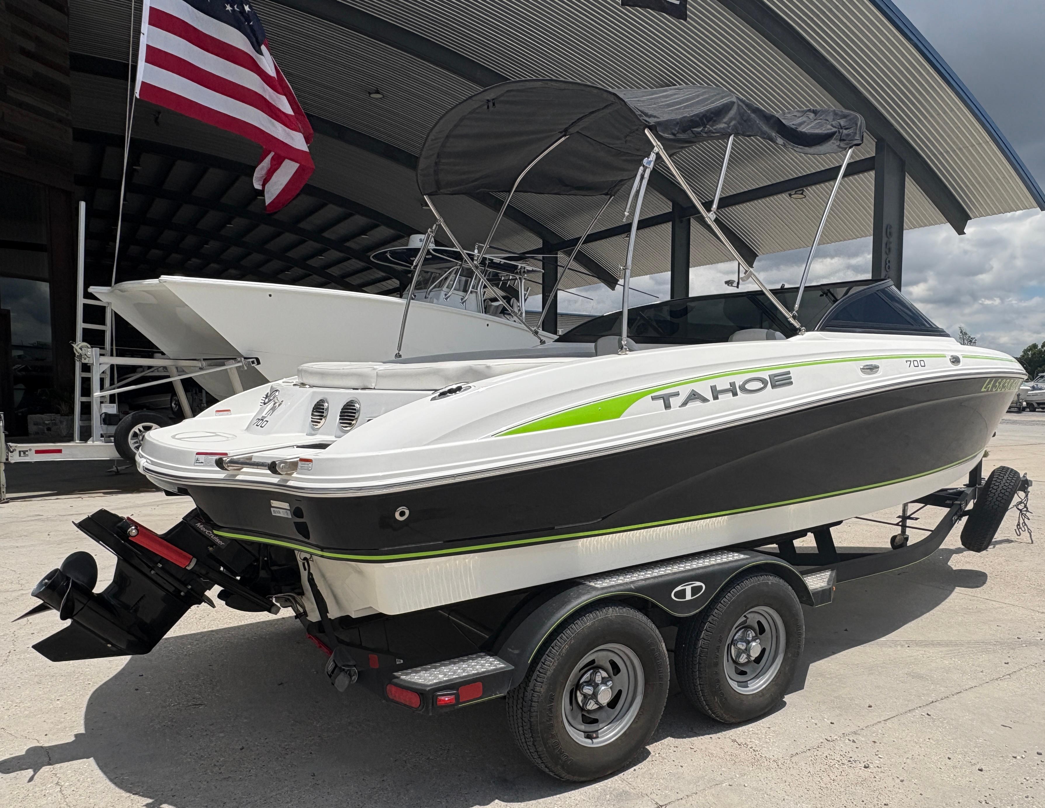 2019 Tahoe 700 boat on trailer, parked outdoors with American flag in background.
