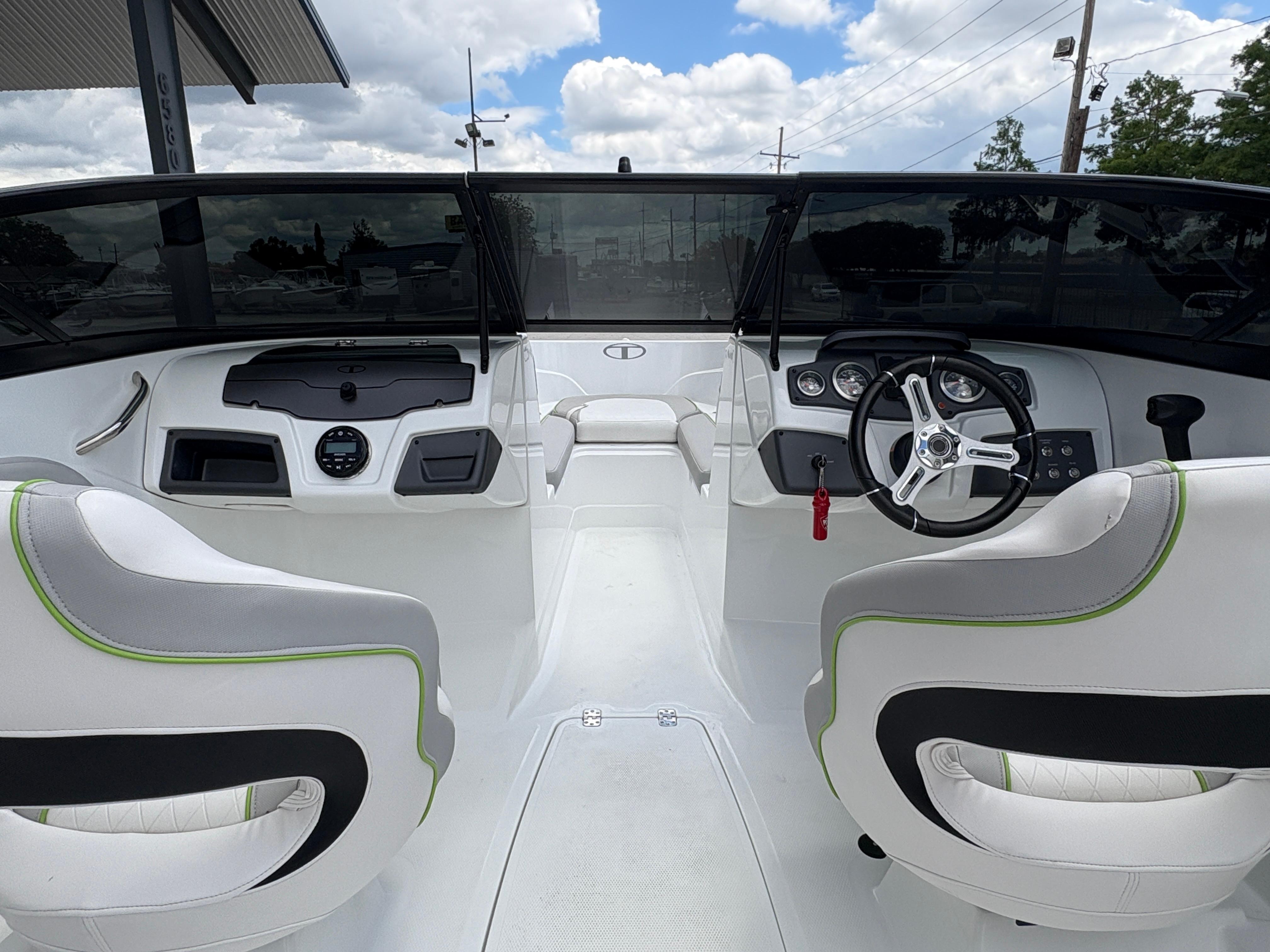 2019 Tahoe 700 boat interior with dual seats, steering wheel, and dashboard under a cloudy sky.