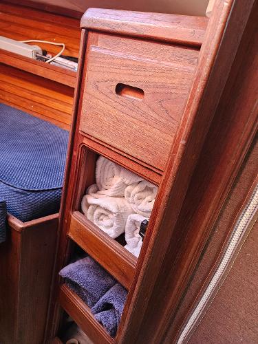 Wooden storage cabinet with towels inside a 1984 Schock NY 36 sailboat interior.