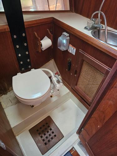 1984 Schock NY 36 boat bathroom with toilet, sink, and wooden cabinetry.
