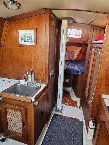 Interior of 1984 Schock NY 36 sailboat with wooden cabinetry and cozy sleeping area.