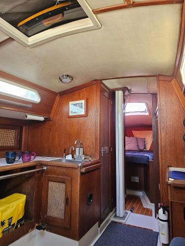 Interior of 1984 Schock NY 36 sailboat, featuring wooden cabinetry and cozy sleeping area.