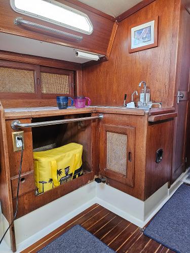 1984 Schock NY 36 yacht interior with wooden cabinetry and compact kitchen area.