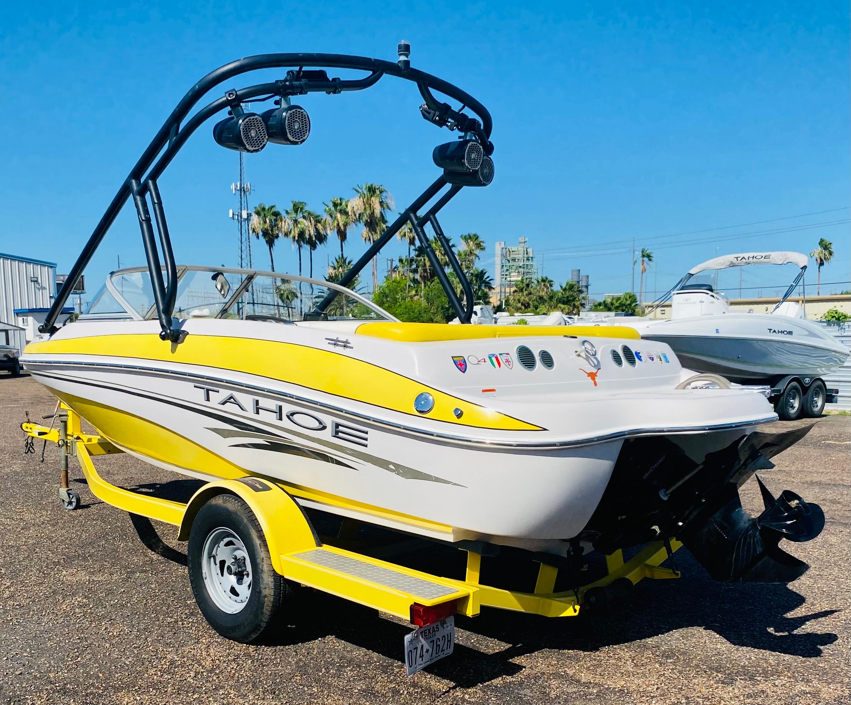 2006 Tahoe Q4 Sport boat with yellow accents on a trailer, parked outdoors.