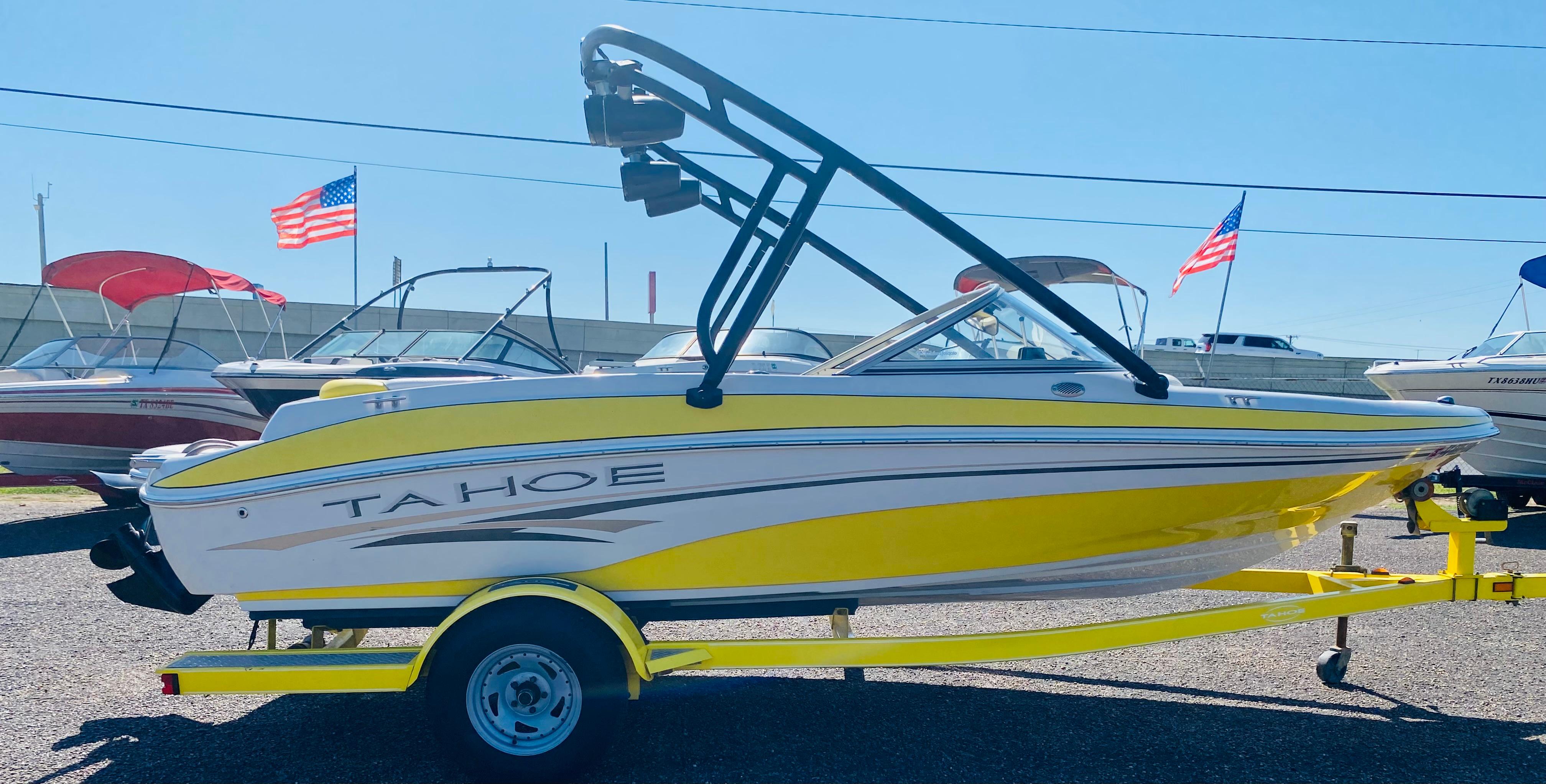2006 Tahoe Q4 Sport boat in yellow on trailer, with American flags in background.