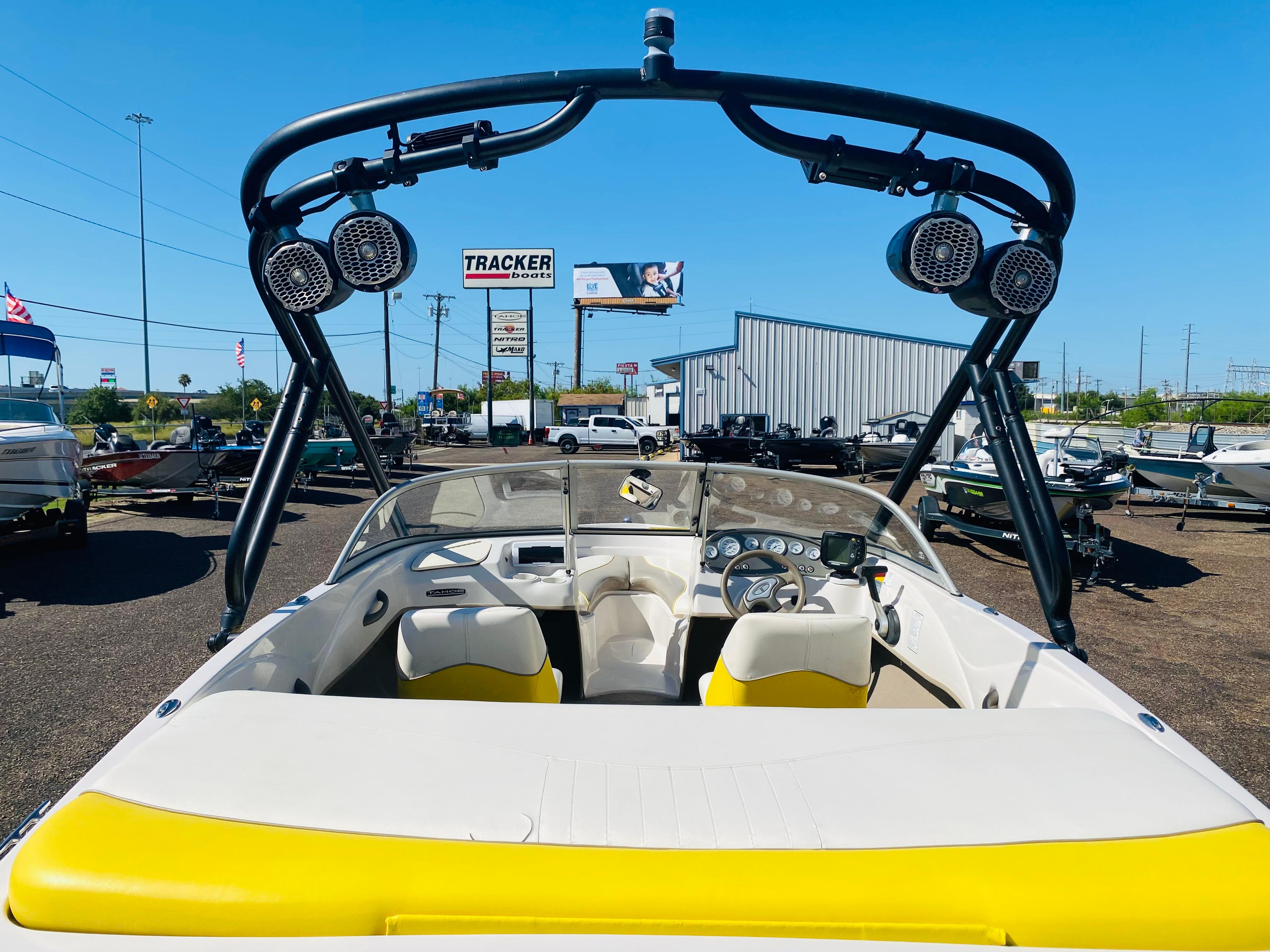 2006 Tahoe Q4 Sport boat with speakers, parked in a dealership lot under clear blue sky.