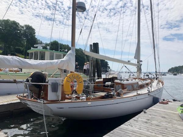 1956 Aage Nielsen 50' Yawl docked at a marina under a partly cloudy sky.