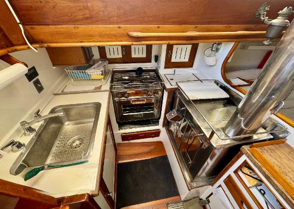 1956 Aage Nielsen 50' Yawl kitchen with stove, sink, and wooden cabinetry.