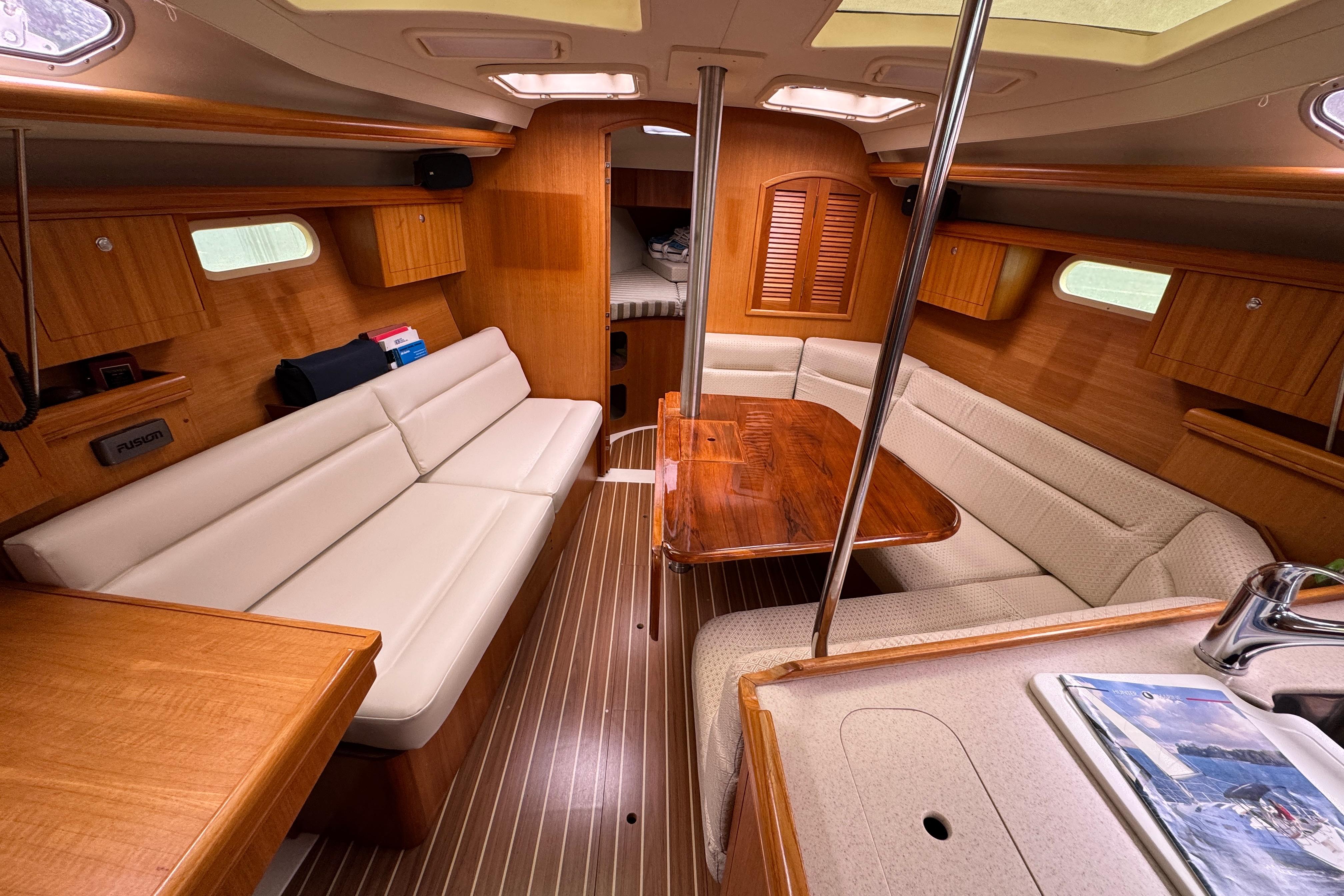Luxurious interior of a 2004 Hunter 386 sailboat with wood finishes and comfortable seating.