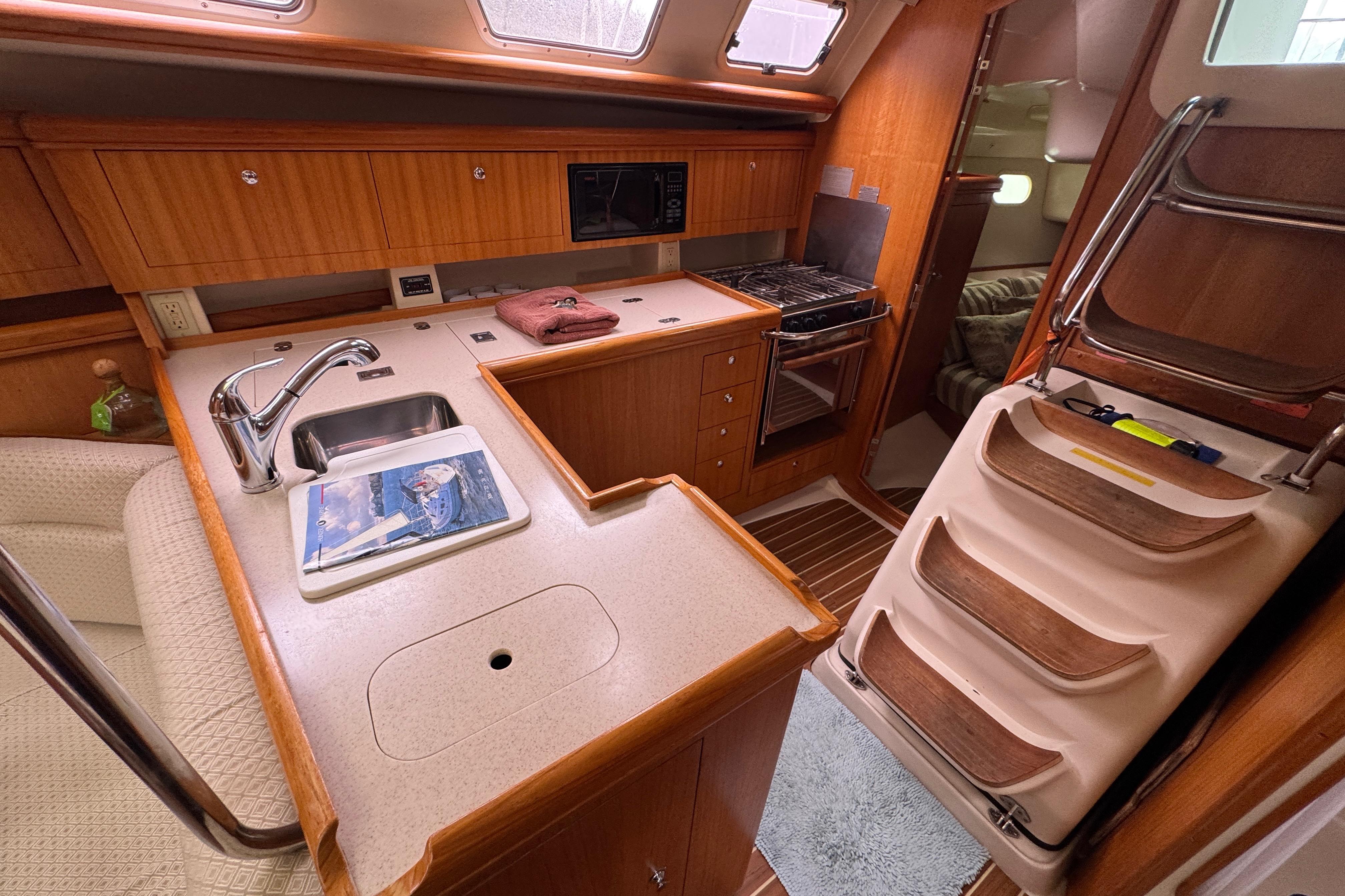 Interior of 2004 Hunter 386 sailboat kitchen with wood cabinetry and modern appliances.