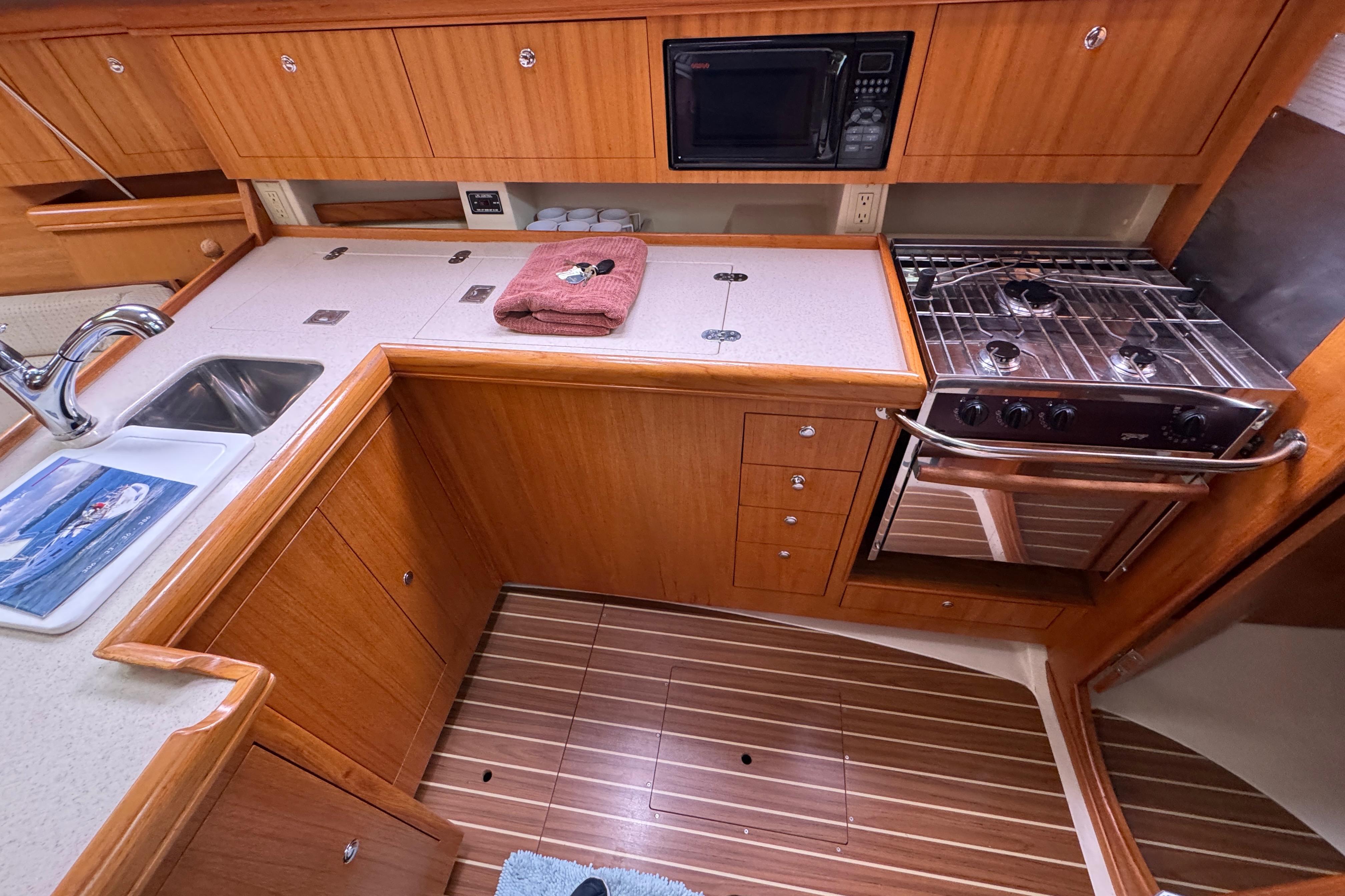 2004 Hunter 386 yacht kitchen with wooden cabinetry, stove, sink, and microwave.