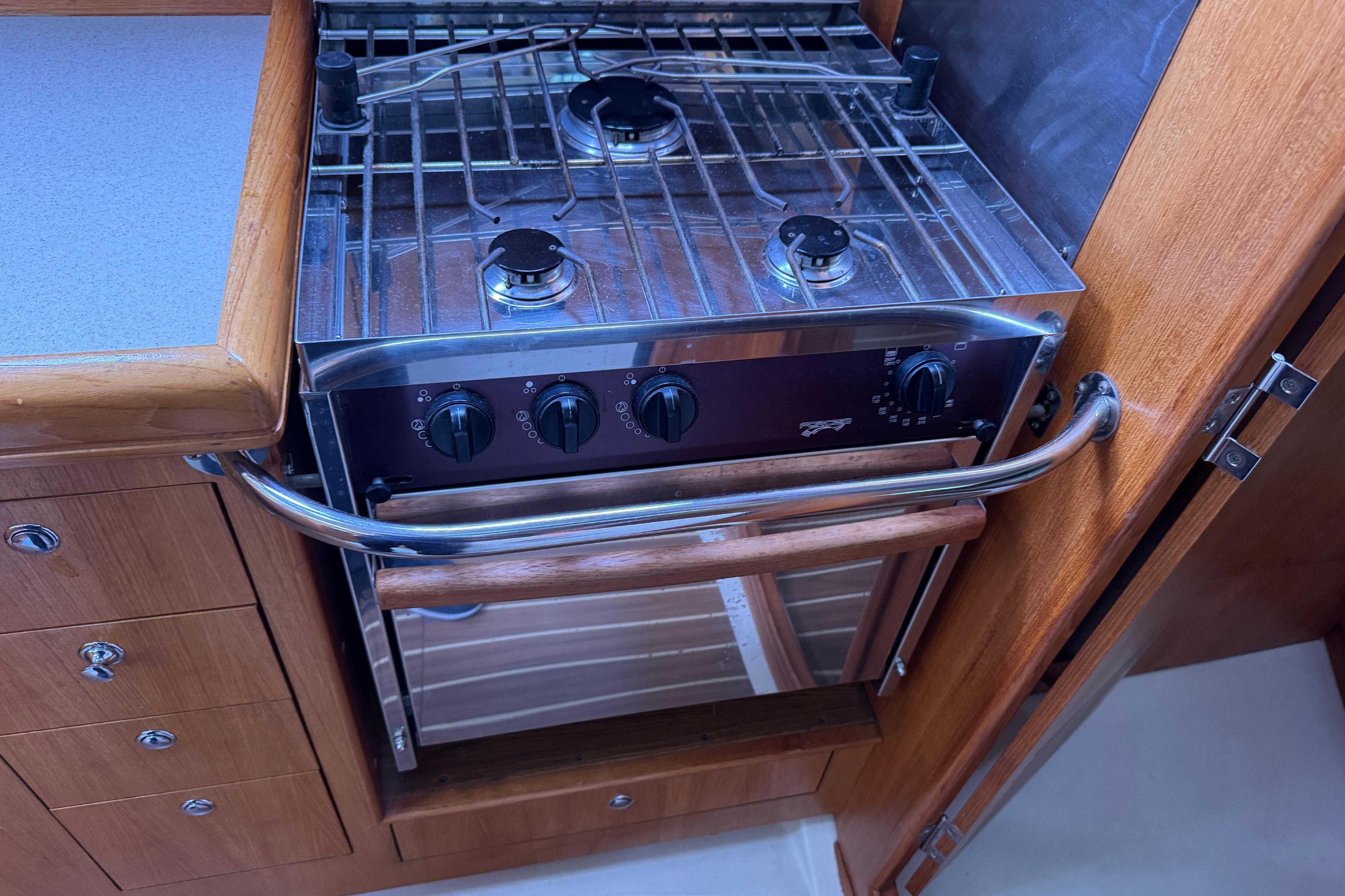 Stove and oven in 2004 Hunter 386 yacht kitchen, featuring wooden cabinetry.