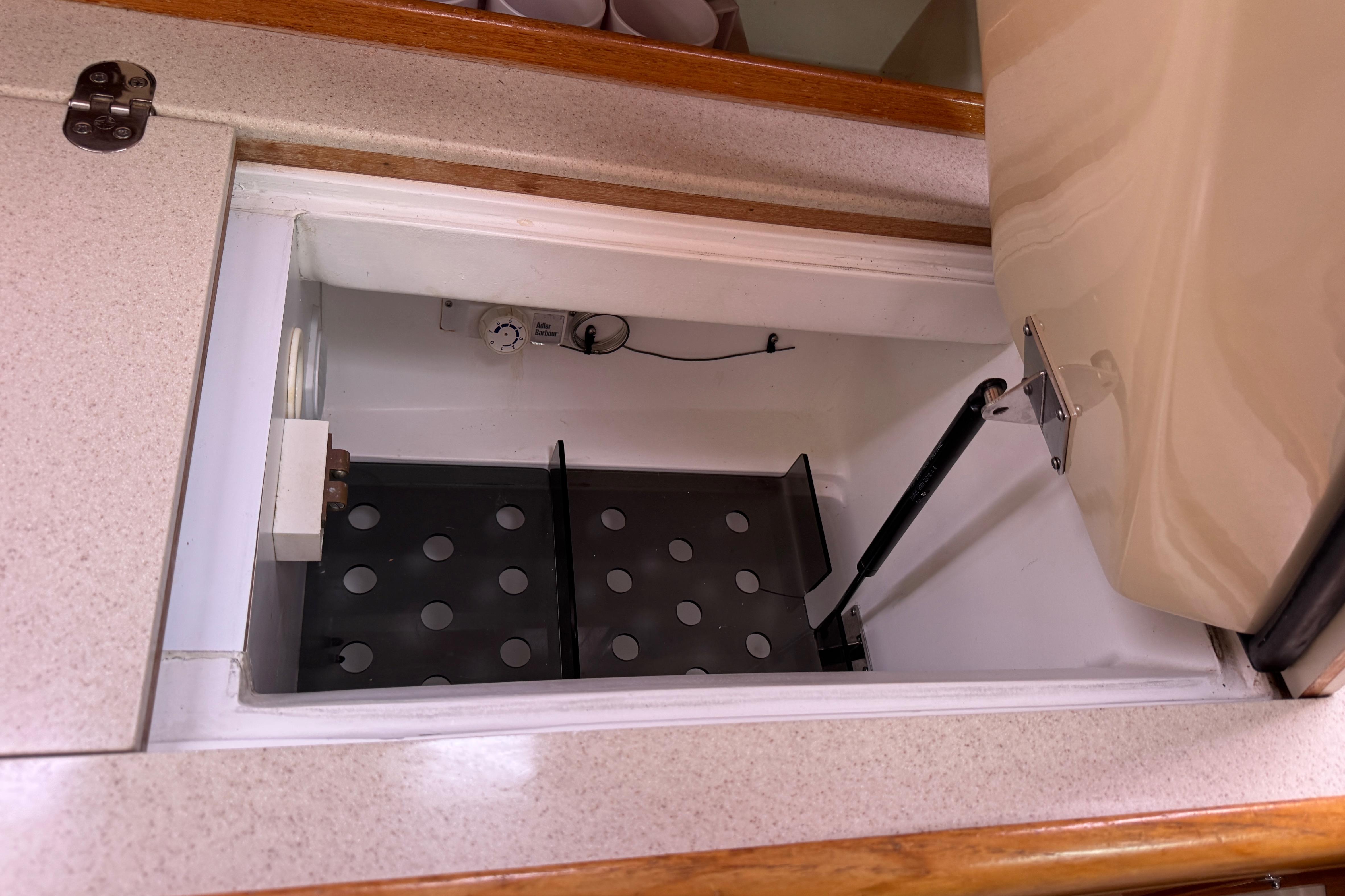 Open storage compartment in 2004 Hunter 386 boat with hydraulic lift and perforated shelf.