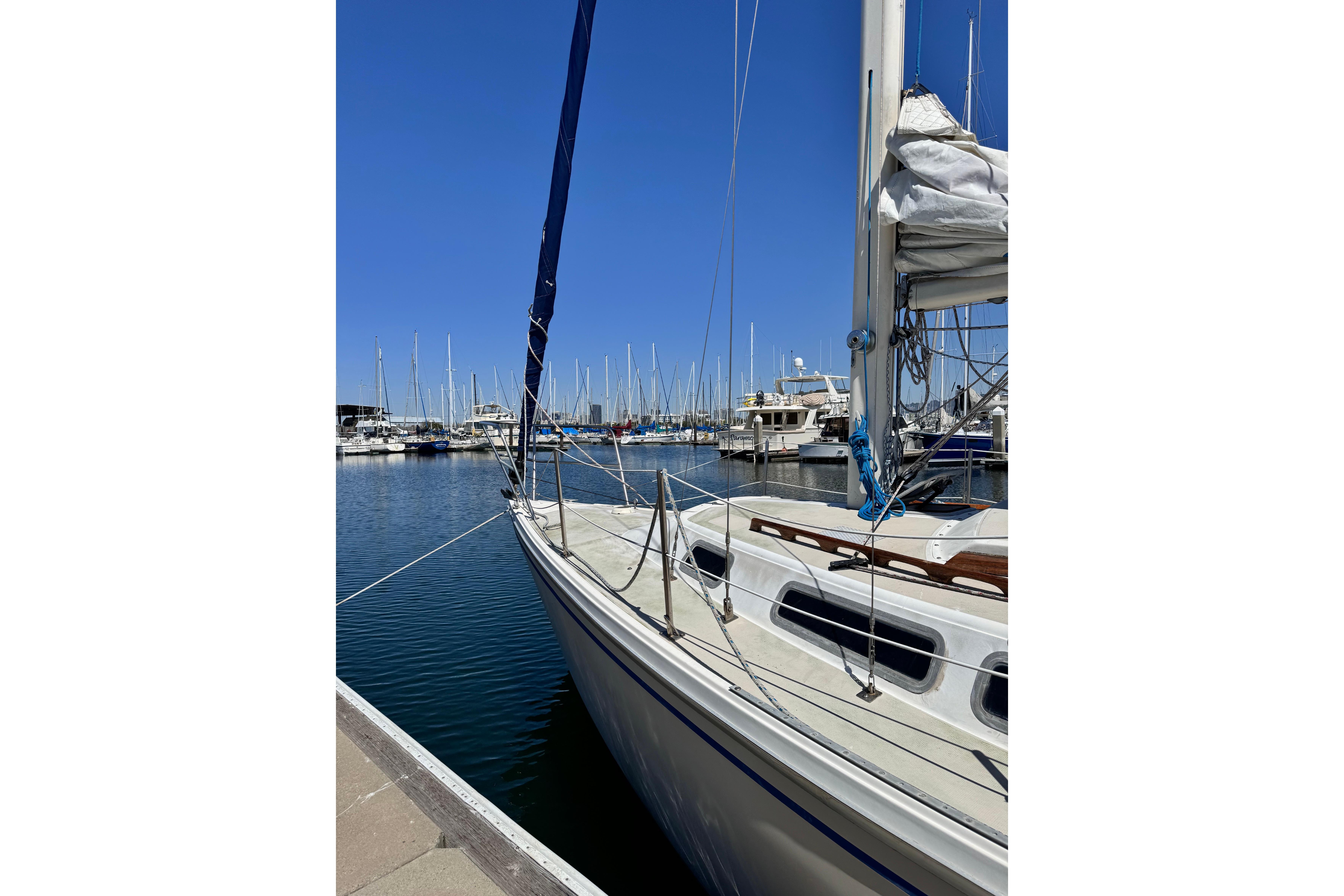 1980 Catalina 30 sailboat docked in a marina under clear blue skies.