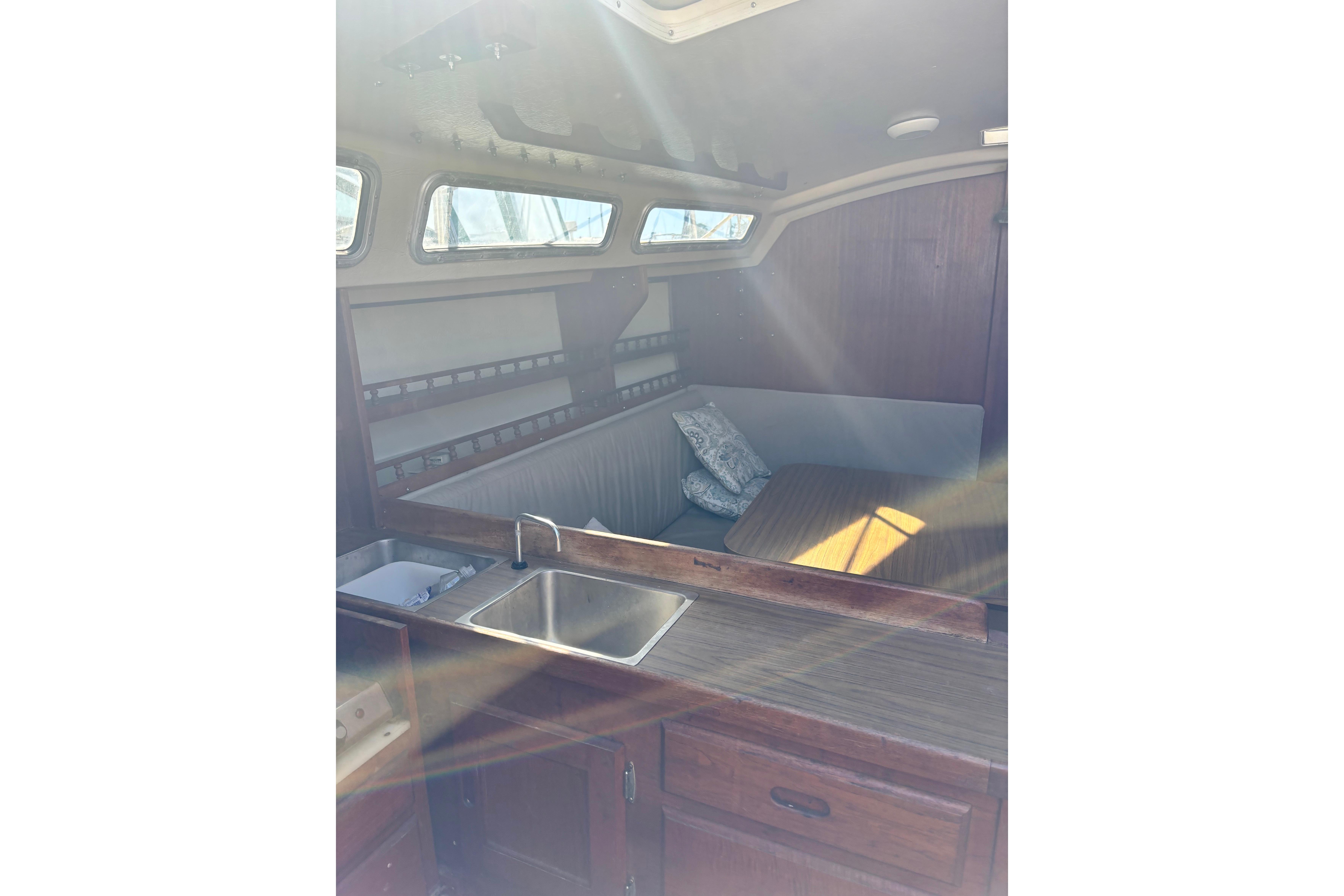 Interior of 1980 Catalina 30 sailboat with cozy seating and kitchenette.