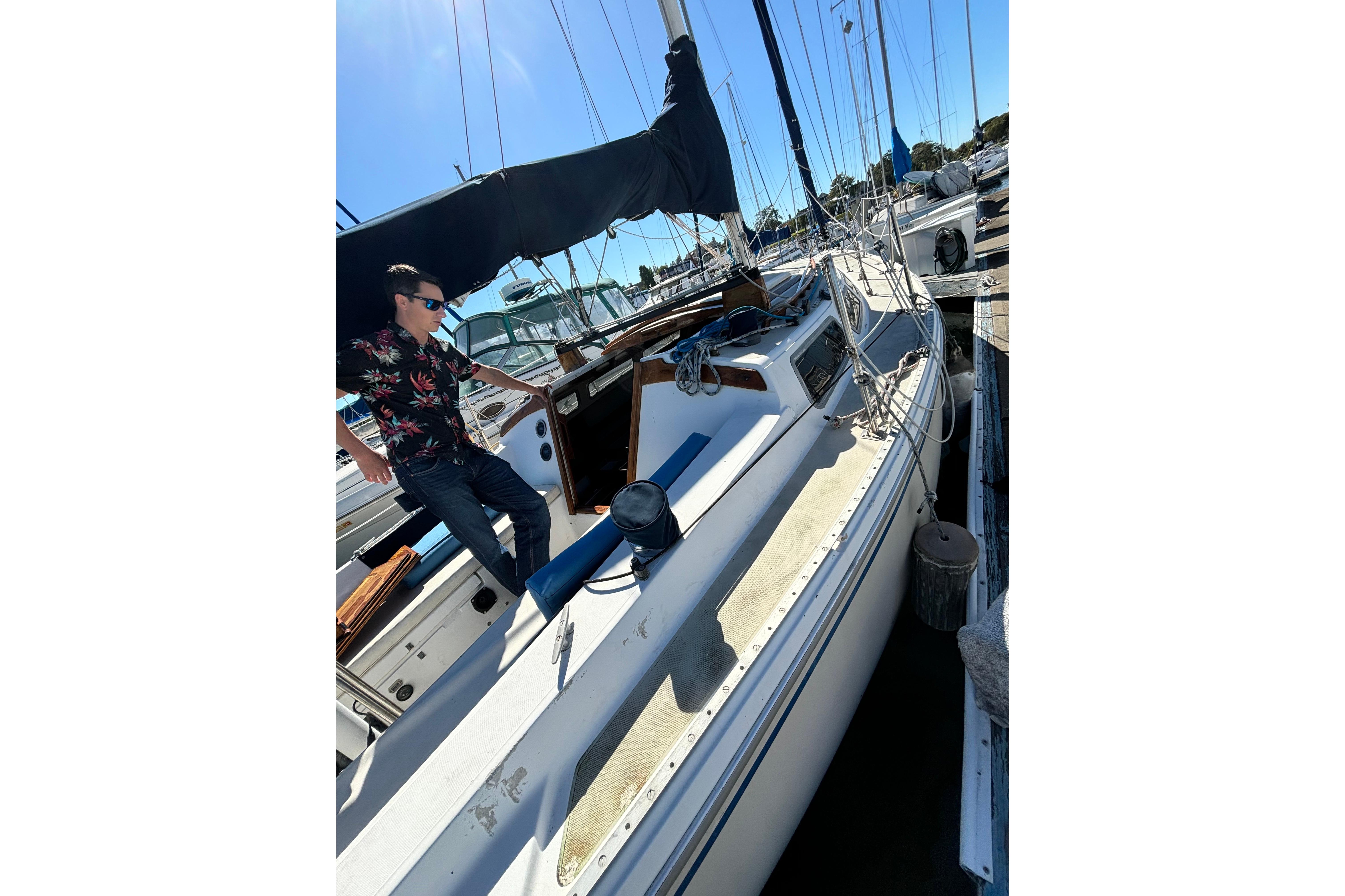 Man on 1980 Catalina 30 sailboat in marina, sunny day, wearing sunglasses.