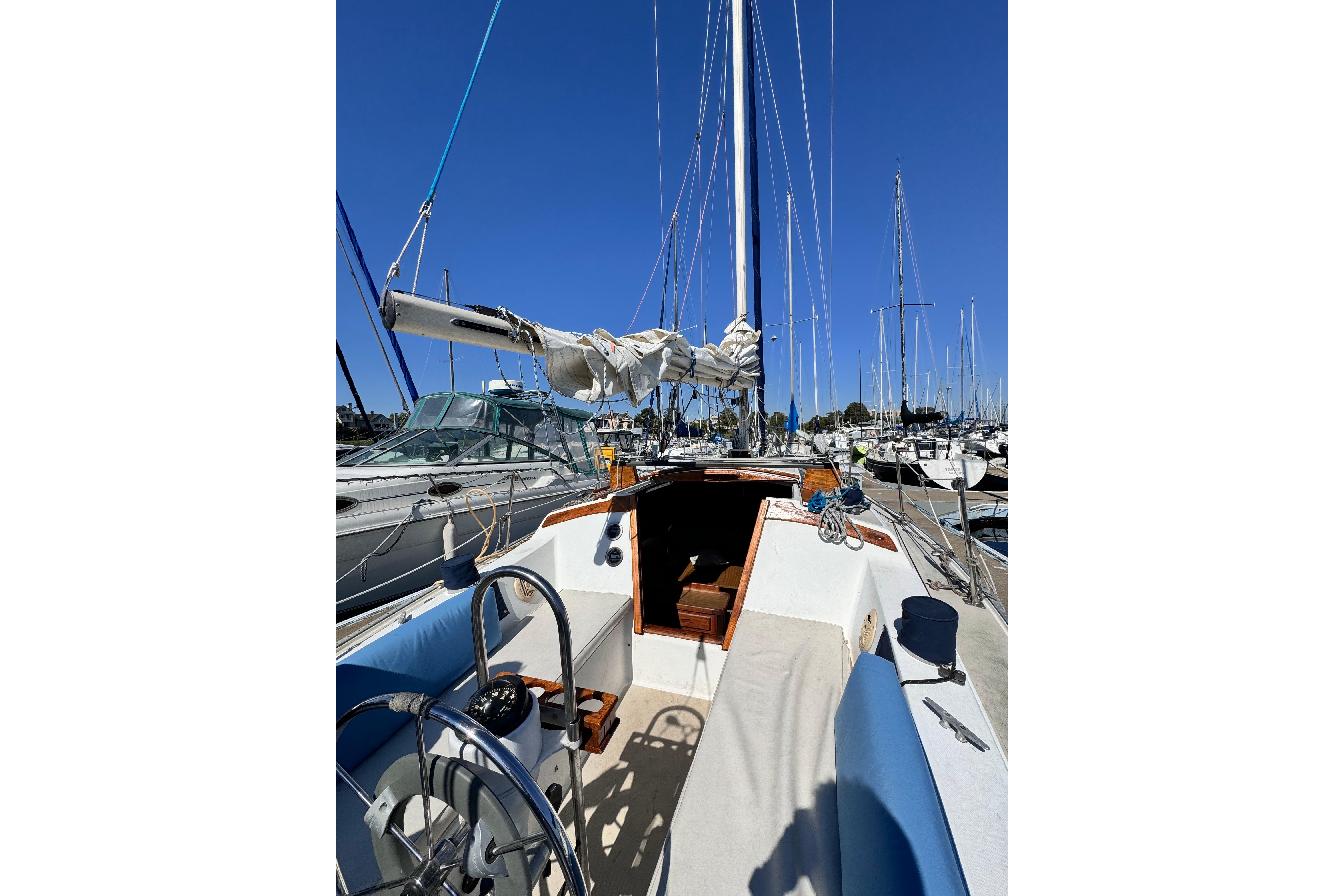 1980 Catalina 30 sailboat docked in marina, featuring cockpit and steering wheel.